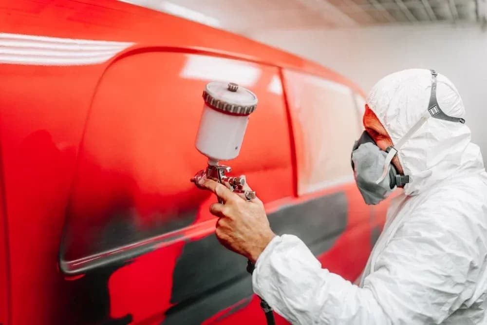 Technician spraying car paint