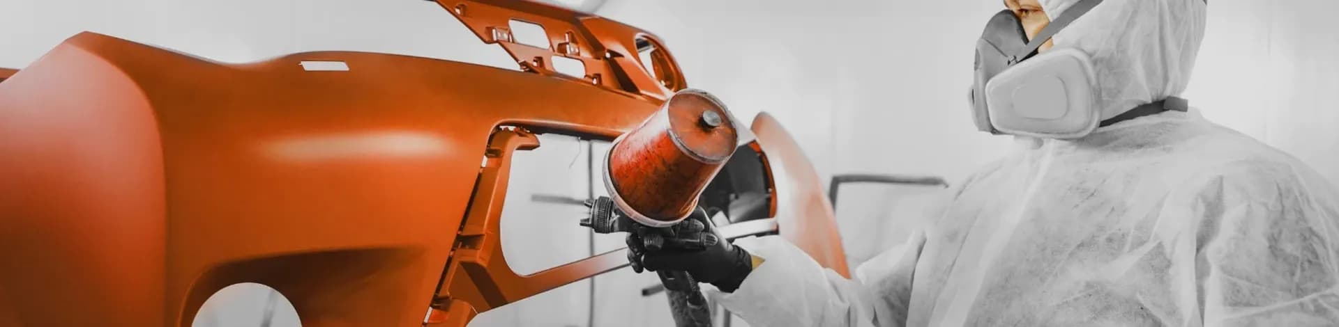 Technician painting a car bumper
